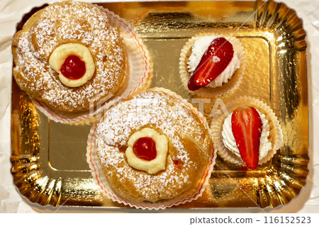 Italian dessert Zeppole di San Giuseppe, zeppola baked puffs made from choux pastry, filled and decorated with custard cream and cherry. Traditional italian dessert Italian dessert Zeppole di San Giuseppe, zeppola baked puffs made from choux pastry, filled and decorated with custard cream and cherry. Traditional italian dessert 116152523
