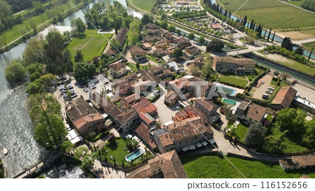 Beautiful little village aerial view of the mill village of Borghetto sul Mincio in the south of Lake Garda, in Veneto, Italy. Drone footage of the small medieval village  116152656