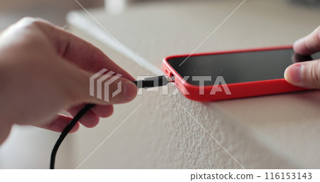 Closeup male hands connecting cable for transfer data. Unrecognizable man plugging cable into smartphone. 116153143