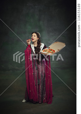 Humorous ads for pizza brands. Portrait of young woman, royal person in rich dress, eating pizza against vintage green background. Humorous ads for pizza brands. Portrait of young woman, royal person in rich dress, eating pizza against vintage green background. 116153189