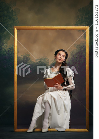 Woman in Regency-era white dress sitting in gold frame, holding open book, against painted background. Timeless reading 116153272