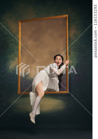 Hidden truth. Young elegant woman in white prior attire stepping out picture frame with shocked and impressed face on vintage background. Hidden truth. Young elegant woman in white prior attire stepping out picture frame with shocked and impressed face on vintage background. 116153293