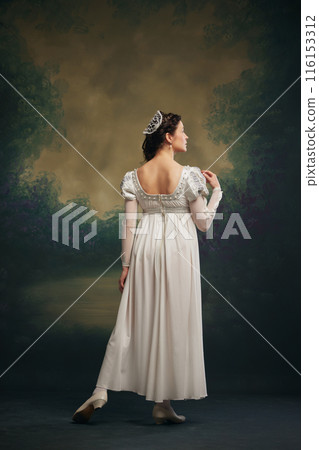 Timeless Grace. Elegant young woman in white dress with silver hair accessory standing against vintage green background. Juliette Timeless Grace. Elegant young woman in white dress with silver hair accessory standing against vintage green background. Juliette 116153312