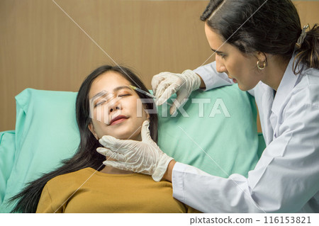Doctor in white gown and protective glove giving female patient medical injection in temporal. Close up 116153821