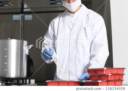 Male kitchen staff packing food into lunch boxes 116154359