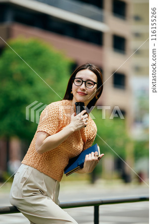 A young woman operating a smartphone 116155266