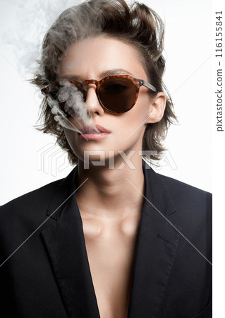 Smoking Beautiful woman with short hair in sunglasses. sexy girl in suit releasing smoke from mouth Smoking Beautiful woman with short hair in sunglasses. sexy girl in suit releasing smoke from mouth 116155841
