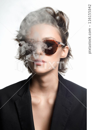 Smoking Beautiful woman with short hair in sunglasses. sexy girl in suit releasing smoke from mouth Smoking Beautiful woman with short hair in sunglasses. sexy girl in suit releasing smoke from mouth 116155842