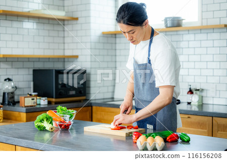 Young man in kitchen with vegetables 116156208