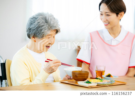 Caregiver and elderly person eating 116156237