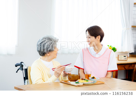 Caregiver and elderly person eating 116156238