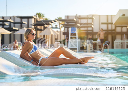 A girl sits near the pool after spa treatments. Turkey, hotel, vacation, travel, girl in a swimsuit 116156525