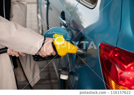 Attractive young woman refueling car at gas station. Female filling diesel at gasoline fuel in car using a fuel nozzle. Petrol concept. Side view 116157622