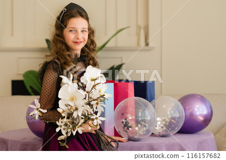 Girl holding flowers and balloons at birthday celebration. Girl holding flowers and balloons at birthday celebration. 116157682