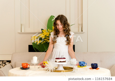 Beautiful birthday girl smiles while standing behind table Beautiful birthday girl smiles while standing behind table 116157684