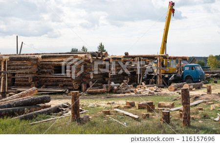 Wooden a log houses under construction with building materials lying nearby Wooden a log houses under construction with building materials lying nearby 116157696