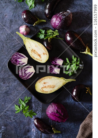 Assortment raw organic of purple vegetables mini eggplants, spring onion, beetroot, radicchio salad, plums, kohlrabi, flower salt over dark metal background. Top view with space. Food frame 116157999