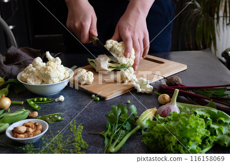 A woman cuts fresh cauliflower at the table 116158069