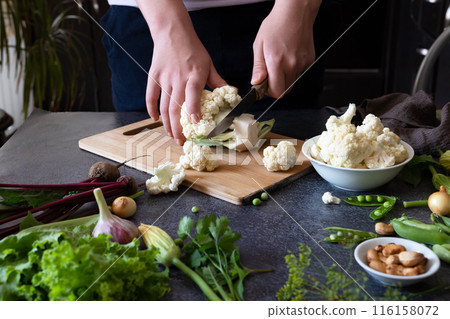 A woman cuts fresh cauliflower at the table A woman cuts fresh cauliflower at the table 116158072