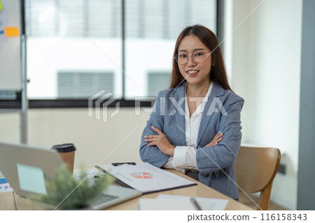 Confident Businesswoman in Office with Laptop and Documents, Smiling and Ready for Work 116158343