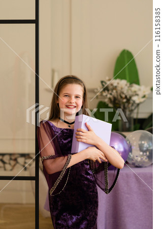 Smiling girl holding gift box at birthday party. Smiling girl holding gift box at birthday party. 116158385