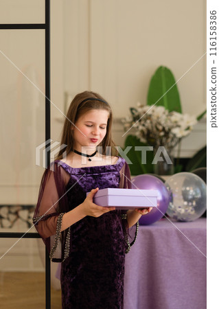 Girl looking at gift box at birthday party. 116158386