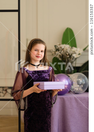 Girl holding gift box and smiling at birthday party. 116158387