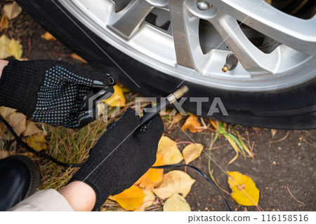man driver hand inflating tires of vehicle, removing tire valve nitrogen cap for checking air pressure and filling air on car wheel at gas station. self service, maintenance and safety 116158516