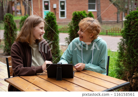 A teenage girl and an older woman spend time together. 116158561