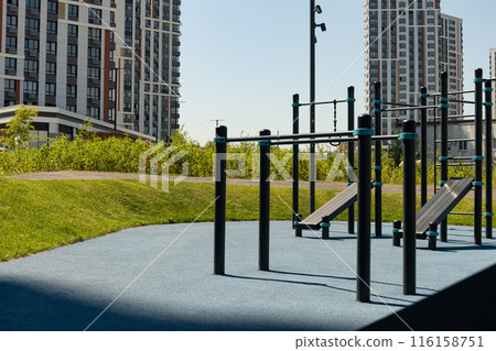 Modern sports playground or gym park for fitness exercises in the city at summer. Outdoors. Public stadium zone. Gym park in courtyard. Modern sports playground or gym park for fitness exercises in the city at summer. Outdoors. Public stadium zone. Gym park in courtyard. 116158751