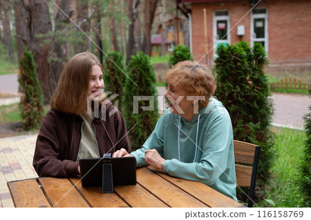 A teenage girl and an older woman spend time together. 116158769