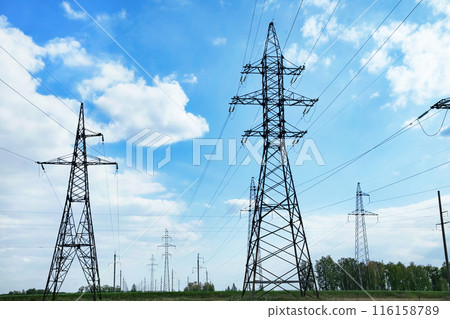 High voltage power lines leading through a green field. Transmission of electricity by means of supports through agricultural areas. High voltage power lines leading through a green field. Transmission of electricity by means of supports through agricultural areas. 116158789