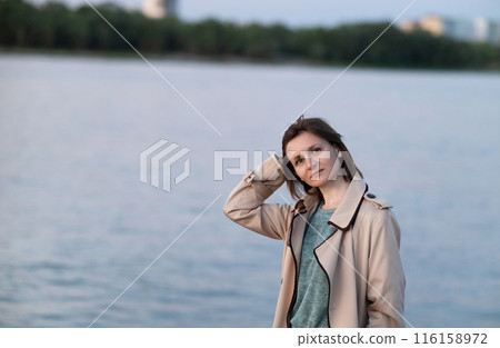 Confident young girl in a white t-shirt and sunglasses walks through the city streets enjoying a summer day. Street photography 116158972