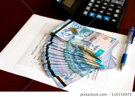 Tenge. Paper Kazakh money and calculator on the table close-up. Tenge. Paper Kazakh money and calculator on the table close-up. 116158975