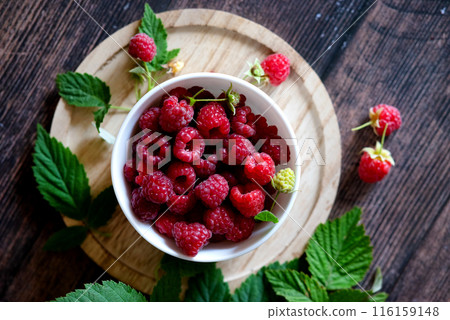 Cup full of fresh ripe garden raspberries against dark rustic background. Shallow DOF with copy space for your text Cup full of fresh ripe garden raspberries against dark rustic background. Shallow DOF with copy space for your text 116159148