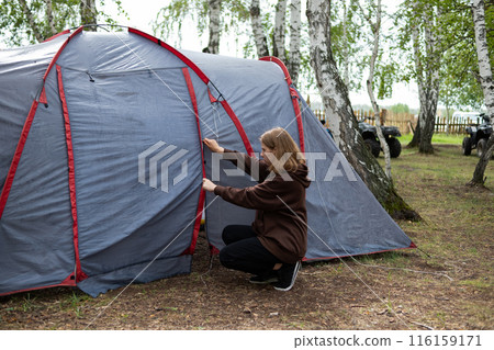 A woman sets up a tent in the forest. Journeys. 116159171
