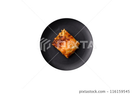 Delicious baked lasagna pasta with meat, sauce, salt, spices and herbs on a dark concrete background 116159545