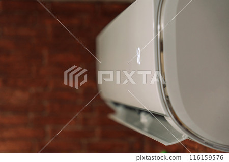 White air conditioner cools the air and hangs on a brick wall 116159576