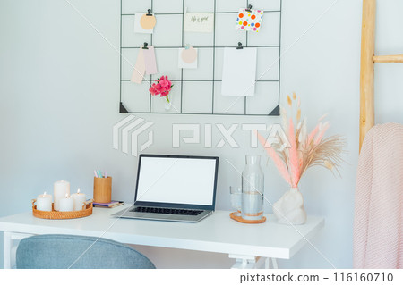 Home office workplace design. White desk with open laptop mockup, grid mood board with peach and pink colors palette and cozy feminine decor, like candles, dried flowers. Inspiration and mood concept. 116160710