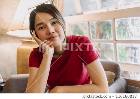 Woman in red is sitting casually in the cozy flowing living room. Woman in red is sitting casually in the cozy flowing living room. 116160818