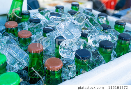Beer Bottles in Ice Cubes, Many Cold Bottle Caps in Box, Iced Chilled Beer Chest, Different Cold Bottles 116161572