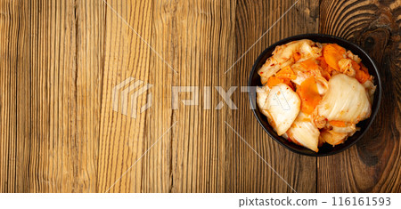 Kimchee in black bowl on wood table. Spicy kim chi pile, hot fermented napa cabbage, traditional jimchi Kimchee in black bowl on wood table. Spicy kim chi pile, hot fermented napa cabbage, traditional jimchi 116161593