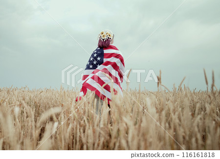 Unrecognizable woman standing with american stars and stripes national flag in rural wheat field landscape. USA, 4th July celebration, US banner, memorial Veterans, election, America, labor 116161818
