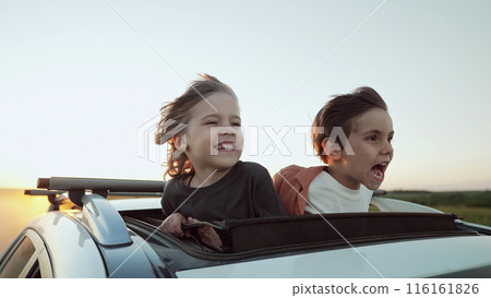 Funny Happy Little Boys Stands In Open Car Sunroof During Trip, Summer.Childhood Funny Happy Little Boys Stands In Open Car Sunroof During Trip, Summer.Childhood 116161826