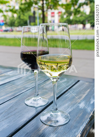 Red wine and white wine glass on restaurant table, wineglasses dinner on restaurant summer terrace Red wine and white wine glass on restaurant table, wineglasses dinner on restaurant summer terrace 116162073