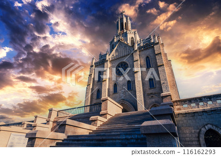 stone ancient medieval Catholic Church in the Gothic style. Cathedral of Sacred Heart of Jesus in Tashkent in Uzbekistan on background of dramatic cloudy sky at sunset 116162293