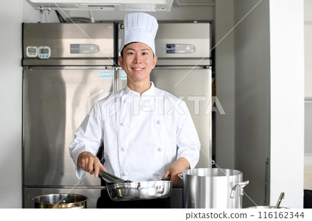 A young asian male chef cooking food in a frying pan in the kitchen A young asian male chef cooking food in a frying pan in the kitchen 116162344