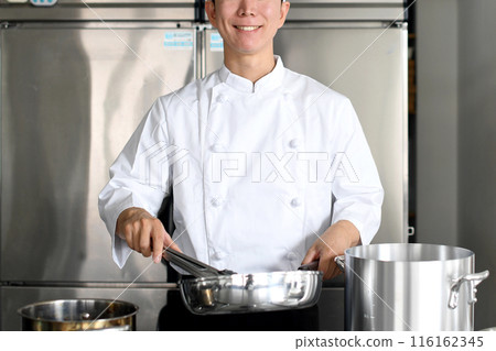 A young asian male chef cooking food in a frying pan in the kitchen A young asian male chef cooking food in a frying pan in the kitchen 116162345