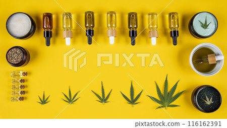 Set of essential oil in a glass bottle, with a pipette on a yellow background, top view 116162391