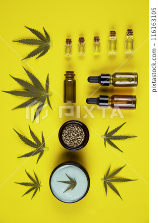 Set of essential oil in a glass bottle, with a pipette on a yellow background, top view 116163105